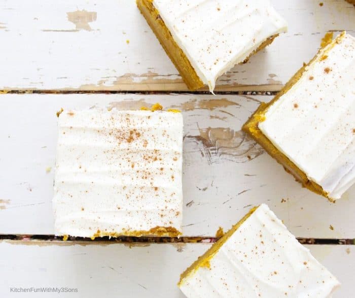 Overhead picture of pumpkin bars with cream cheese frosting sitting on a wooden surface