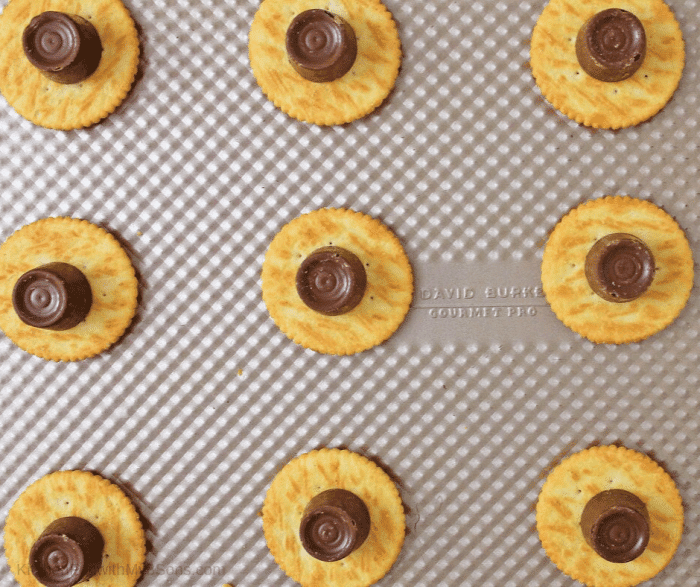 ritz crackers with rolo candy on top sitting on cookie sheet