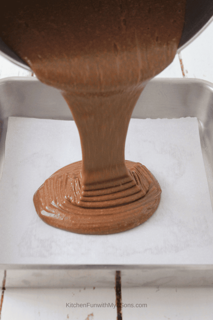 Pouring brownie batter into a metal baking dish