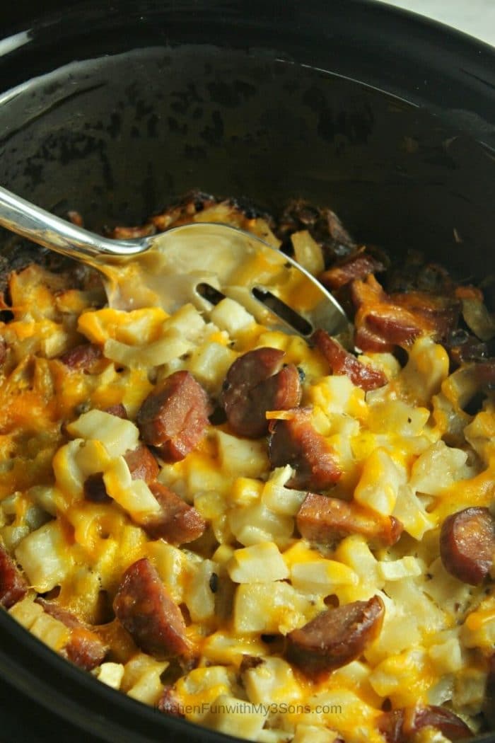 Prepared slow cooker breakfast casserole with a large metal spoon scooping out a serving