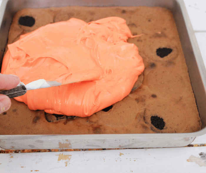 Spreading orange icing on Halloween oreo brownies
