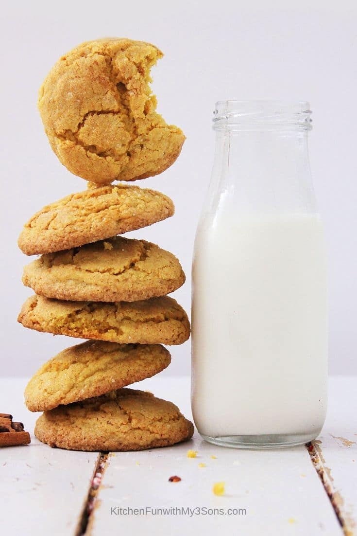 Tall stack of pumpkin sugar cookies next to a bottle of milk