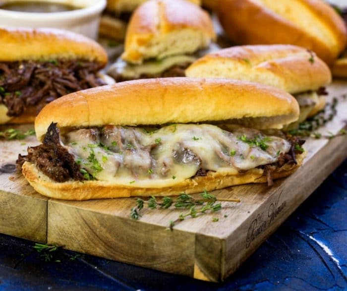 Up close picture of french dip sandwiches on a cutting board ready to serve