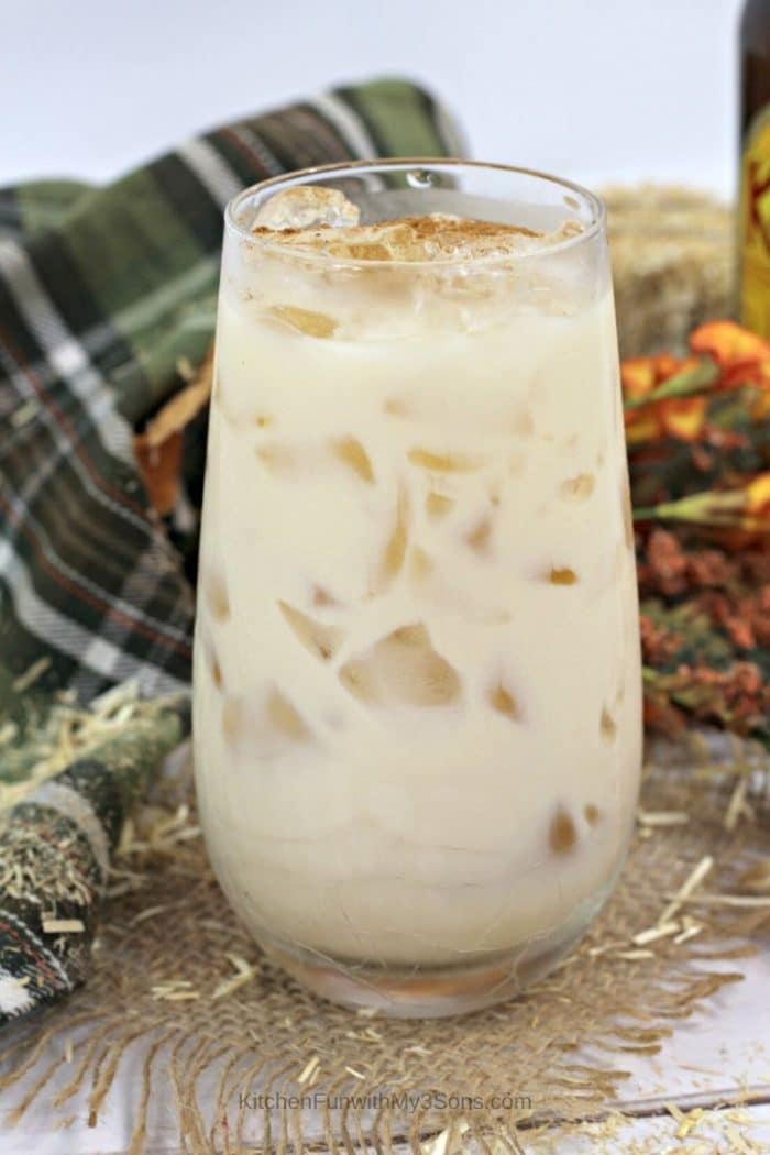 Up close pumpkin white russian in a tall clear glass in front of a plaid cloth