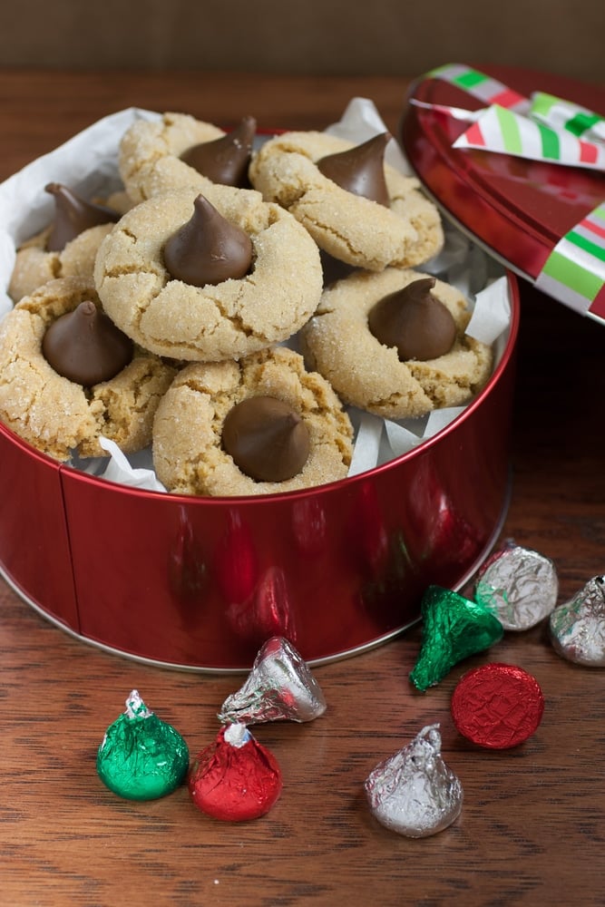 Peanut Butter Kiss cookies in a decorative tin for Christmas gift giving next to hershey kisses