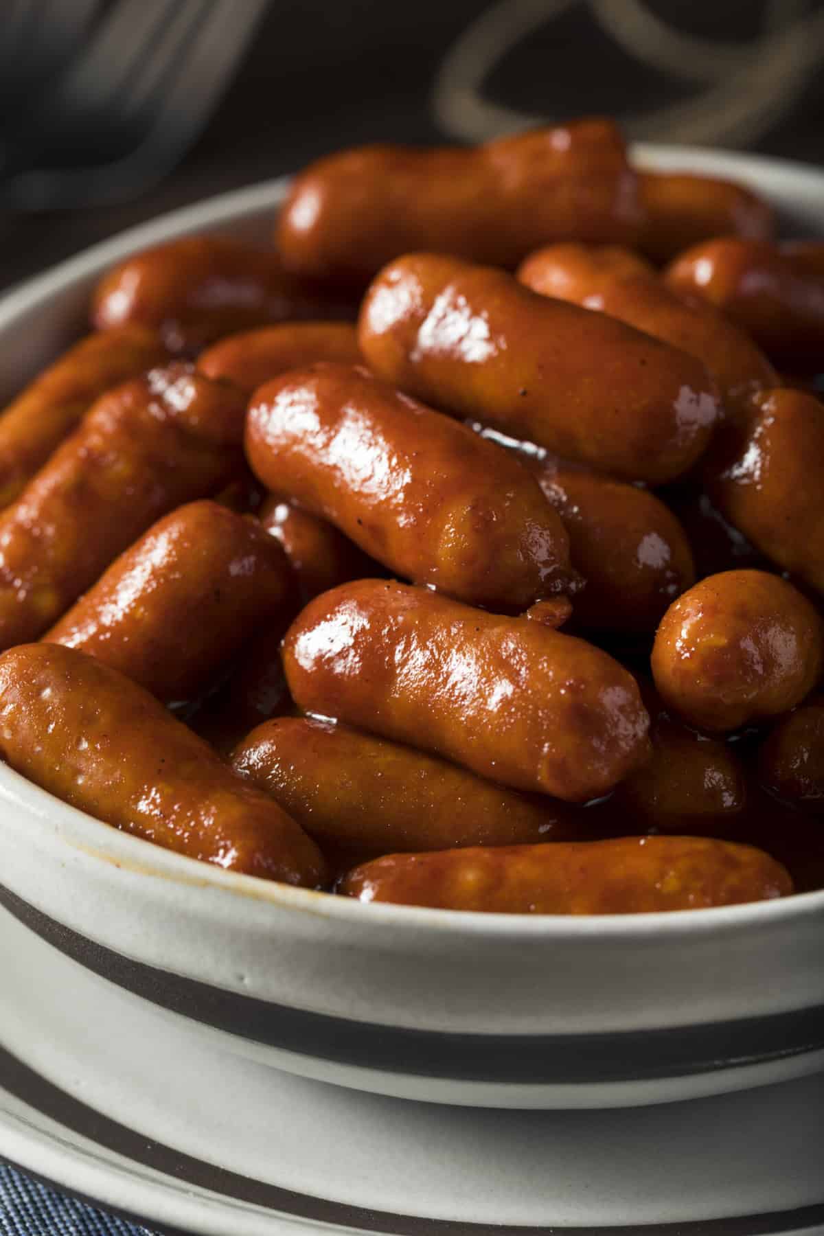 This Little Smokies recipe is made with just 3 ingredients - cocktail sausages, BBQ sauce, and grape jelly. Quick & easy! A bowl of crockpot lil' smokies