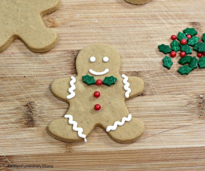 A single gingerbread man cookie ready with candy leaves and berries