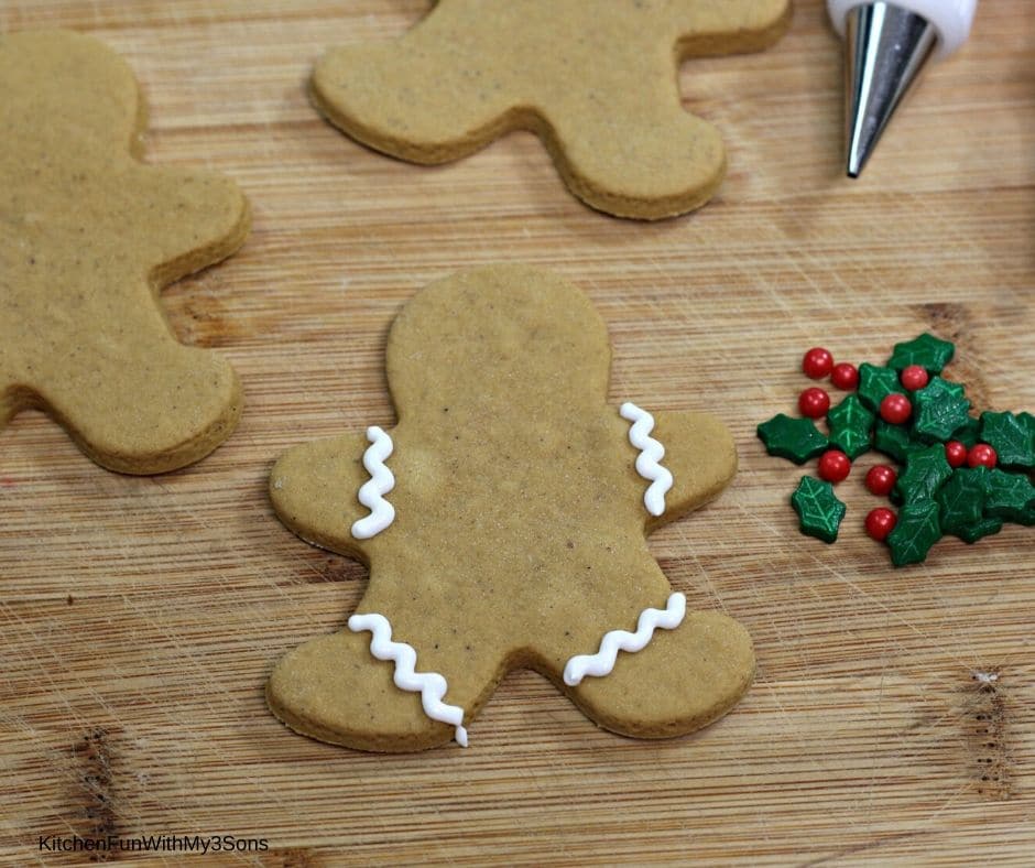 Adding white ribbons on arms and legs of gingerbread man cookies