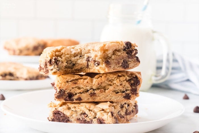 A stack of chocolate chip cookie bars on a white plate