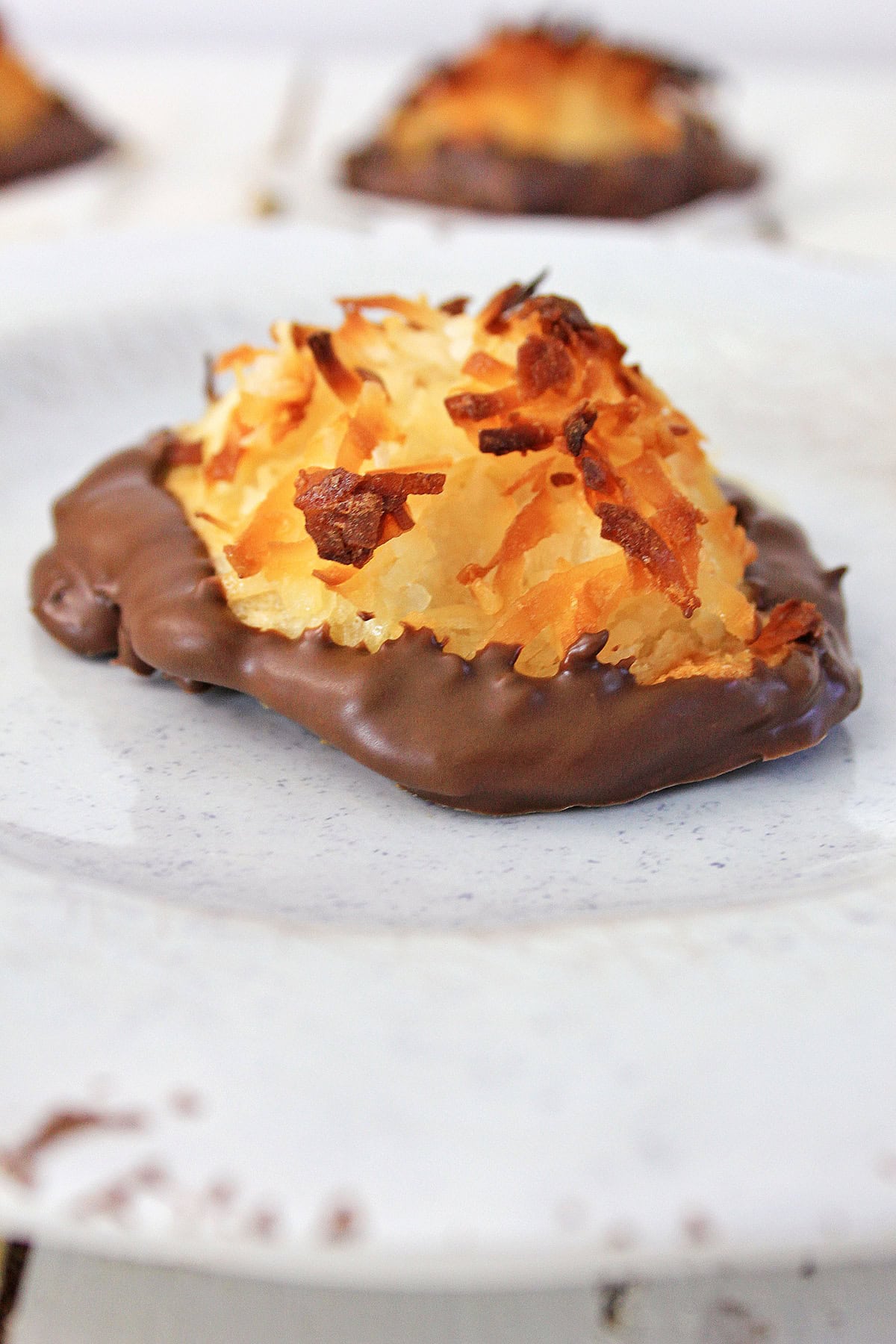A coconut macaroon dipped in chocolate on a plate