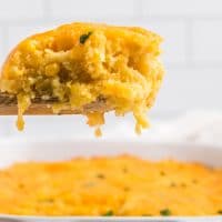 A serving of corn casserole on a wooden spoon
