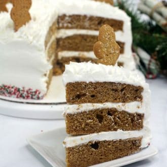 Gingerbread layer cake on a white plate on white table topped with cookie