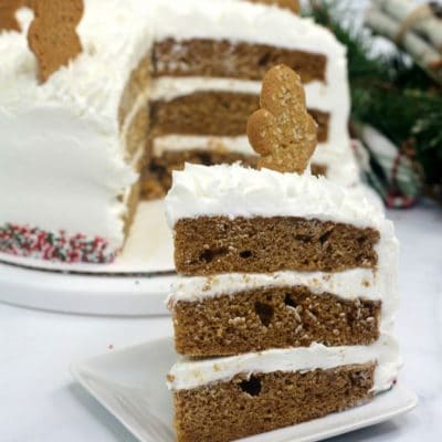 Gingerbread layer cake on a white plate on white table topped with cookie
