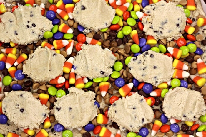 Overhead view of a layer of Halloween candy topped with scoops of chocolate chip cookie dough.