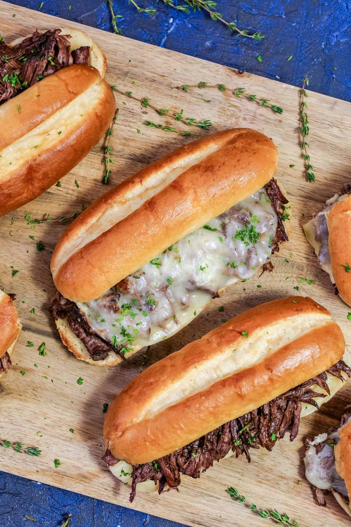 Overhead view of French dip sandwiches on a cutting board