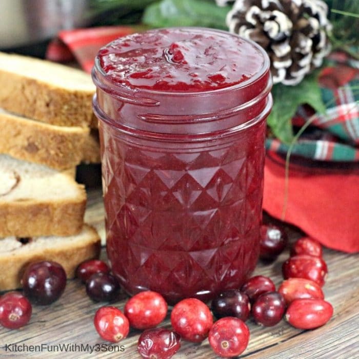 Small mason jar filled with Instant Pot Cranberry Butter in front of holiday decorations