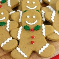 Up close picture of a gingerbread man cookie with green leaf tie and red berry buttons