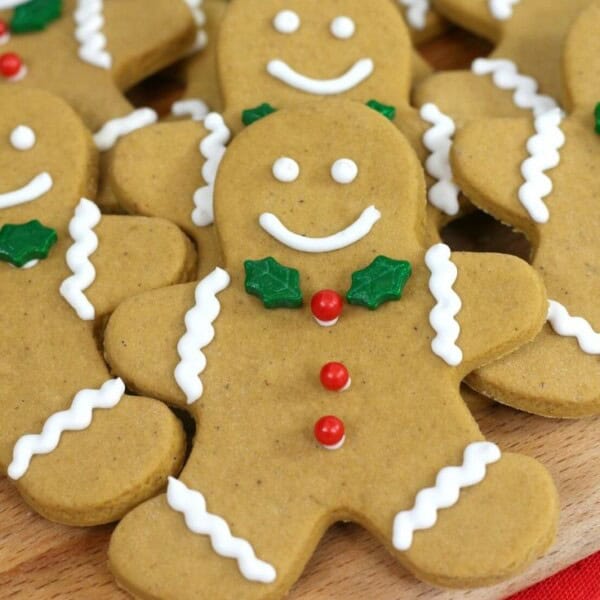 Up close picture of a gingerbread man cookie with green leaf tie and red berry buttons