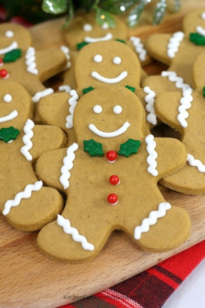 Up close picture of a gingerbread man cookie with green leaf tie and red berry buttons