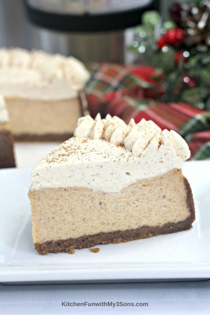 Up close picture of a slice of eggnog cheesecake on a plate in front of holiday decor