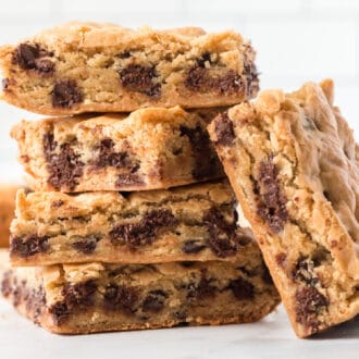 Four chocolate chip cookie bars stacked on each other, with one leaning against the pile