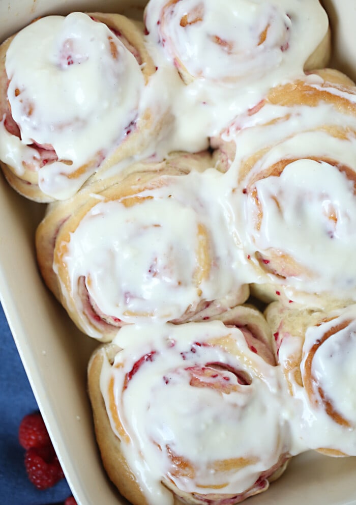 Adding Cream CHeese Frosting on top of Raspberry Sweet Rolls