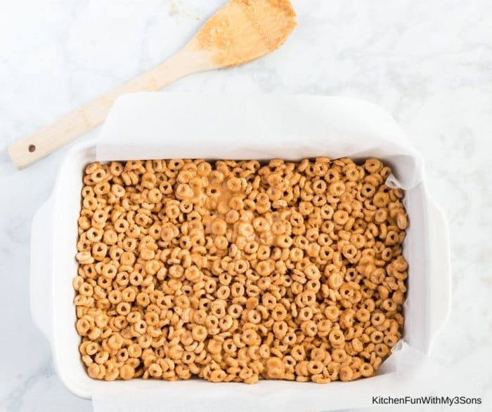 Pressing the cereal mixture down into a baking pan