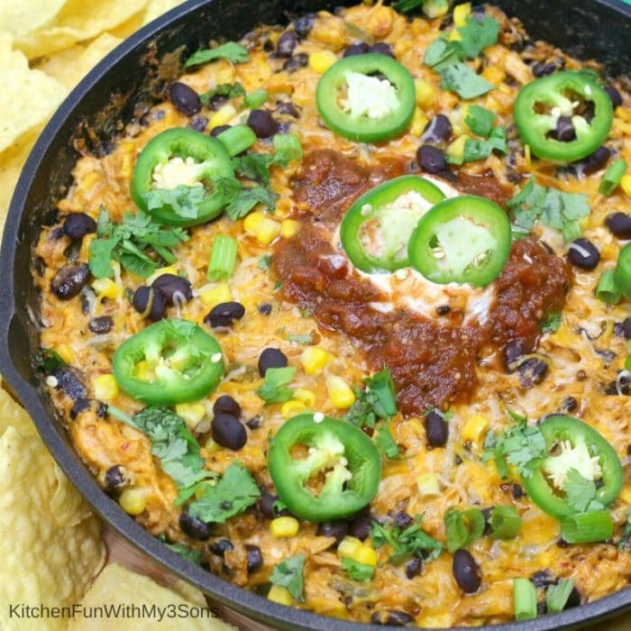 Overhead up close square picture of chicken enchilada dip in a cast iron skillet