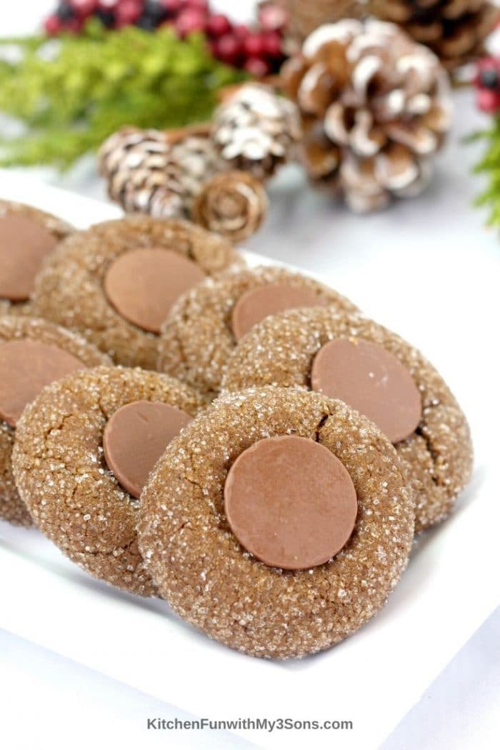 Stacks of gingerbread cookies on a platter with holiday decorations in the background