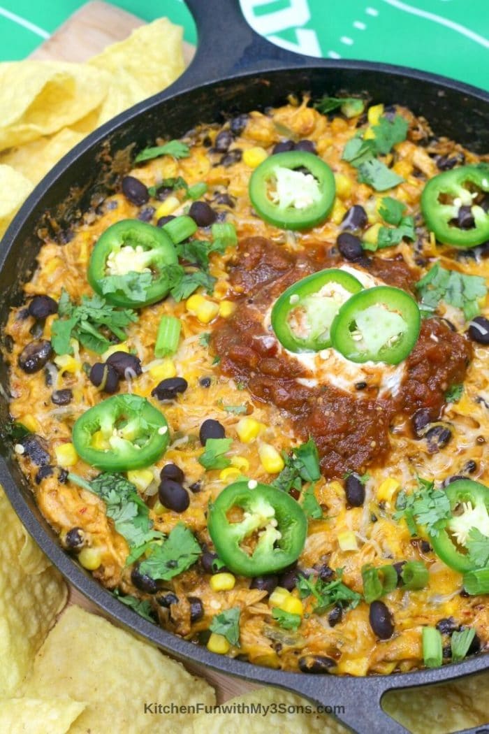 Chicken enchilada dip topped with jalapeno sour cream and salsa