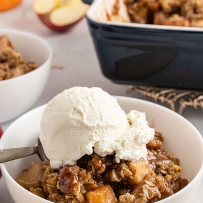 apple crisp in a white bowl with ice cream