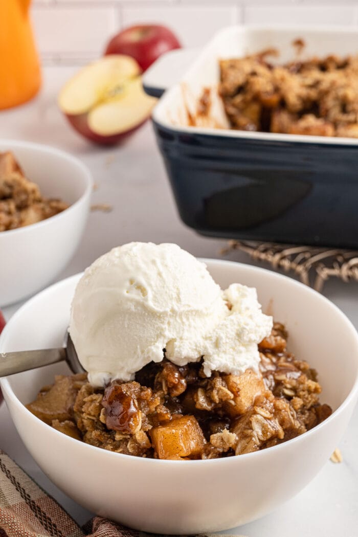 apple crisp in a white bowl with ice cream