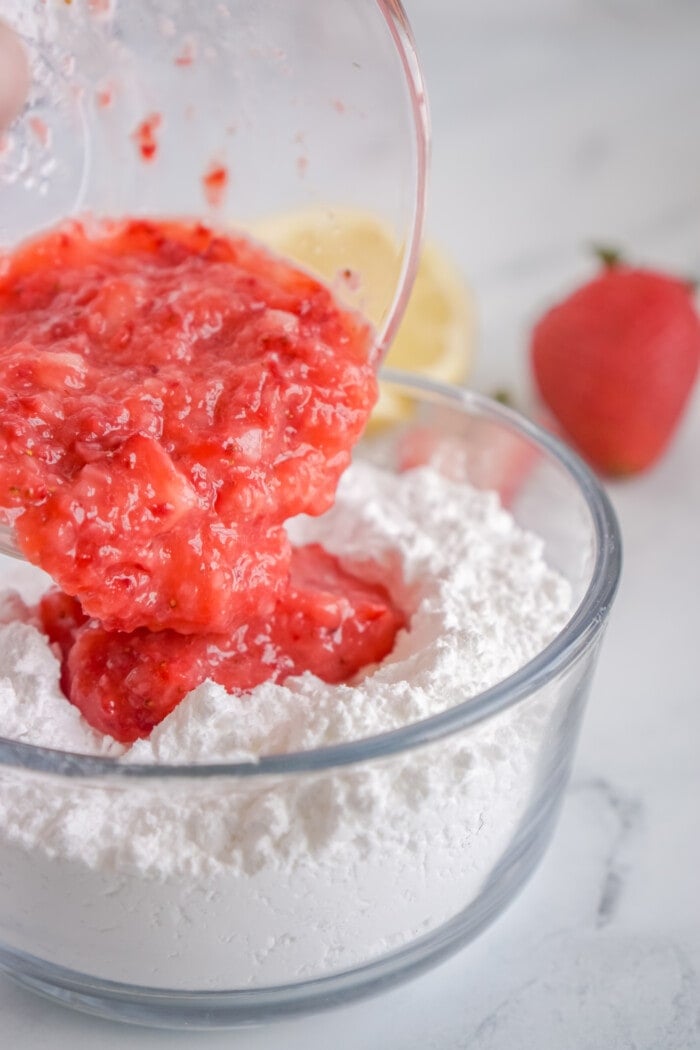 crushed strawberries being added to powdered sugar