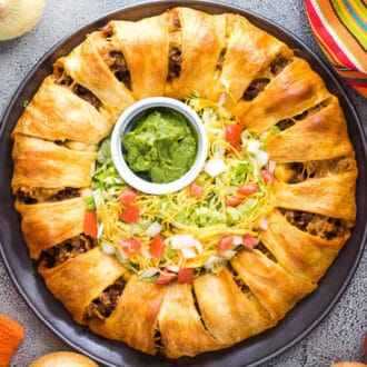 Top view of a baked taco ring on a plate with toppings in the center.