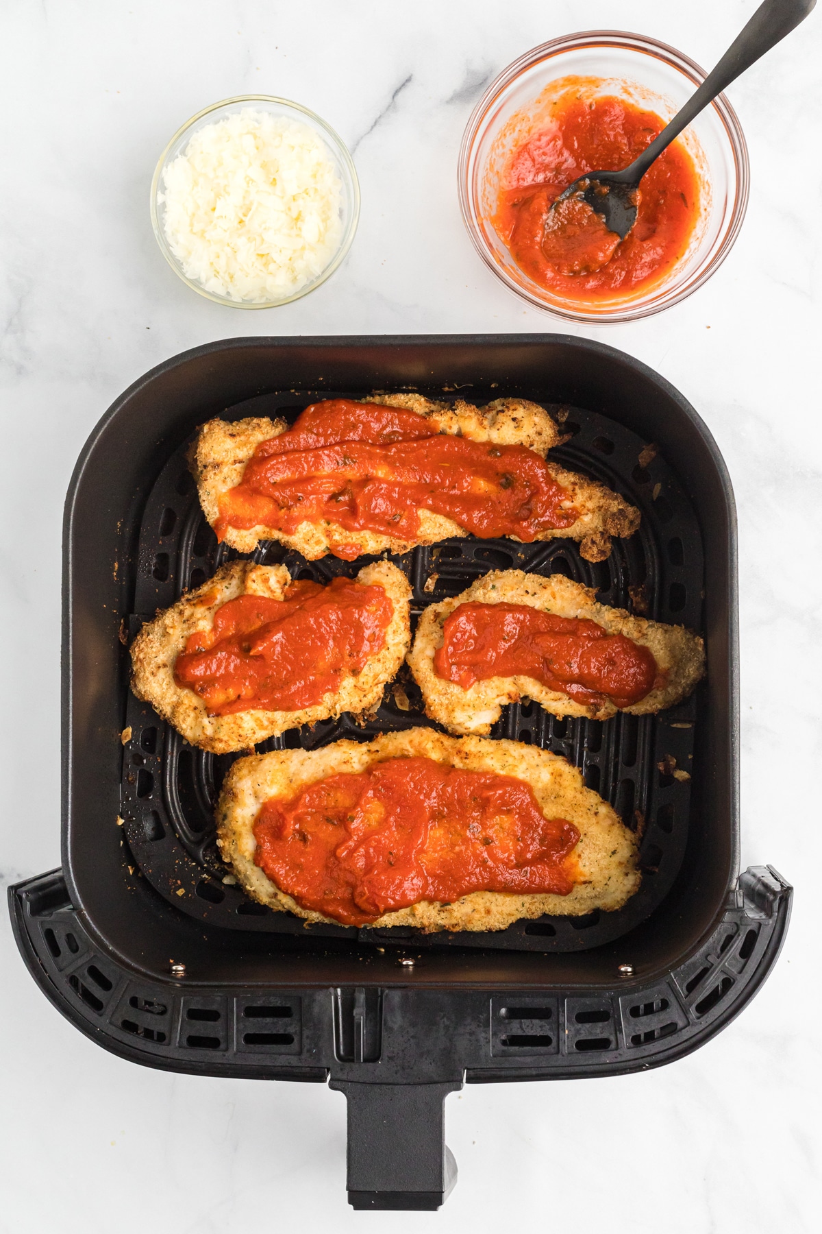 Breaded chicken breasts topped with marinara sauce in the air fryer