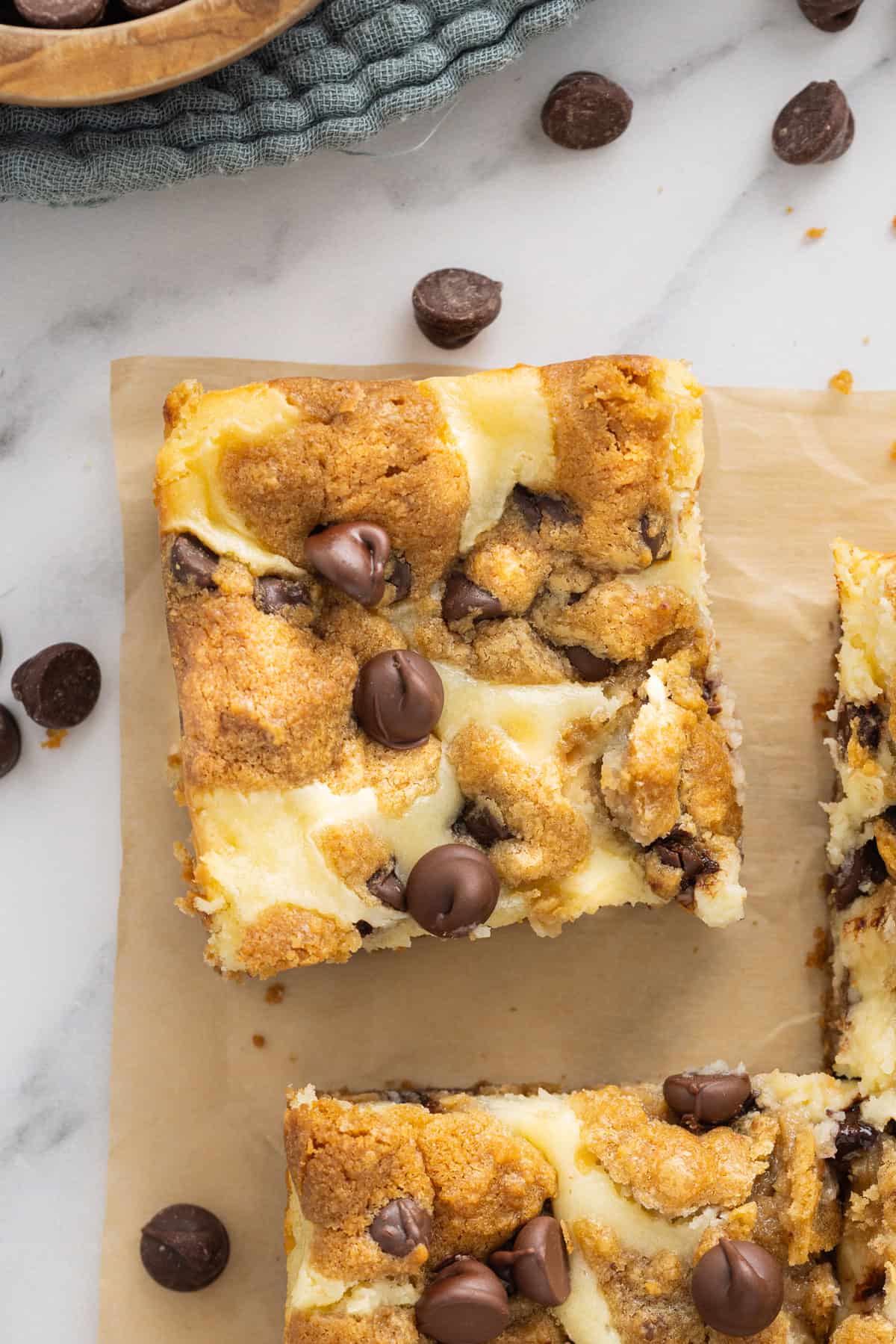 Creamy, tangy cheesecake filling is stuffed between layers of cookie dough in these Chocolate Chip Cheesecake Bars. Overhead view of a chocolate chip cheesecake bar