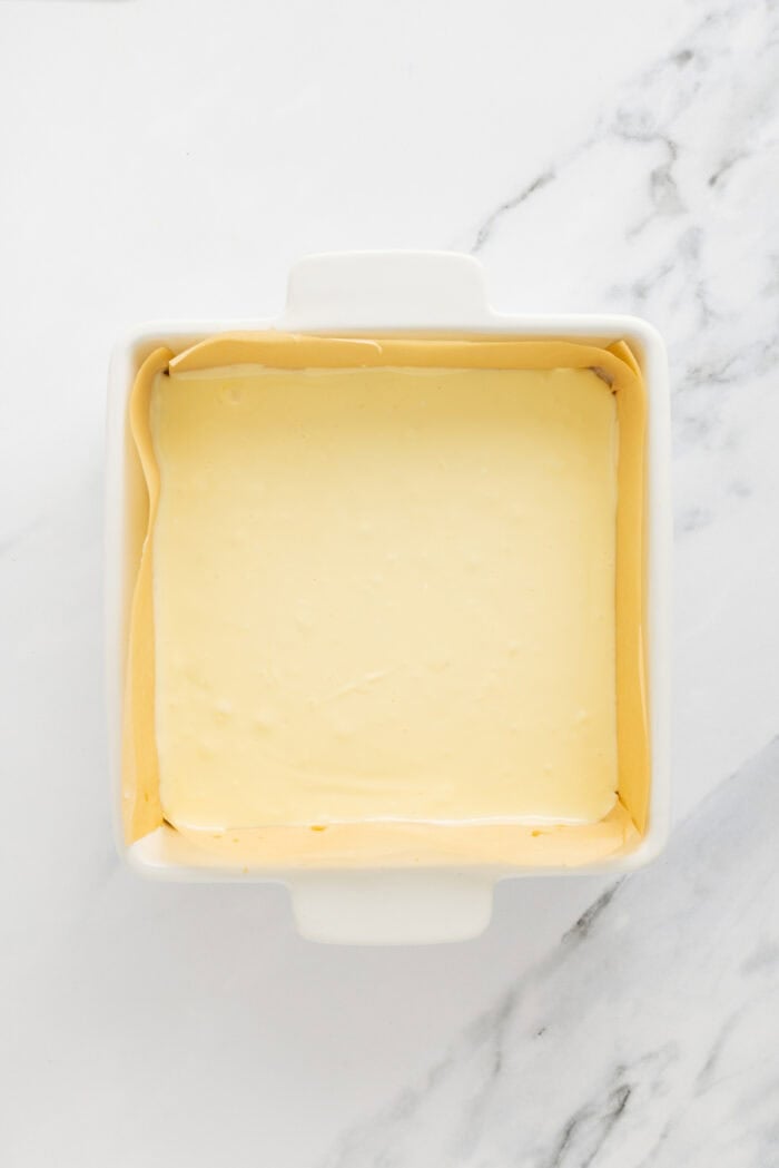 Creamy, tangy cheesecake filling is stuffed between layers of cookie dough in these Chocolate Chip Cheesecake Bars. Cheesecake filling in a square pan