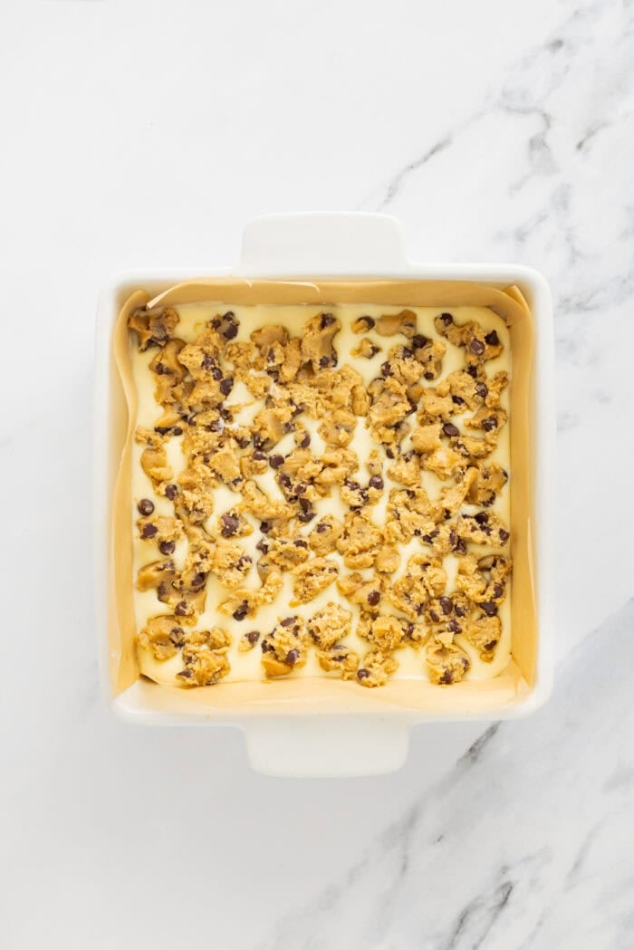 Creamy, tangy cheesecake filling is stuffed between layers of cookie dough in these Chocolate Chip Cheesecake Bars. Chocolate chip cheesecake bars in a square pan