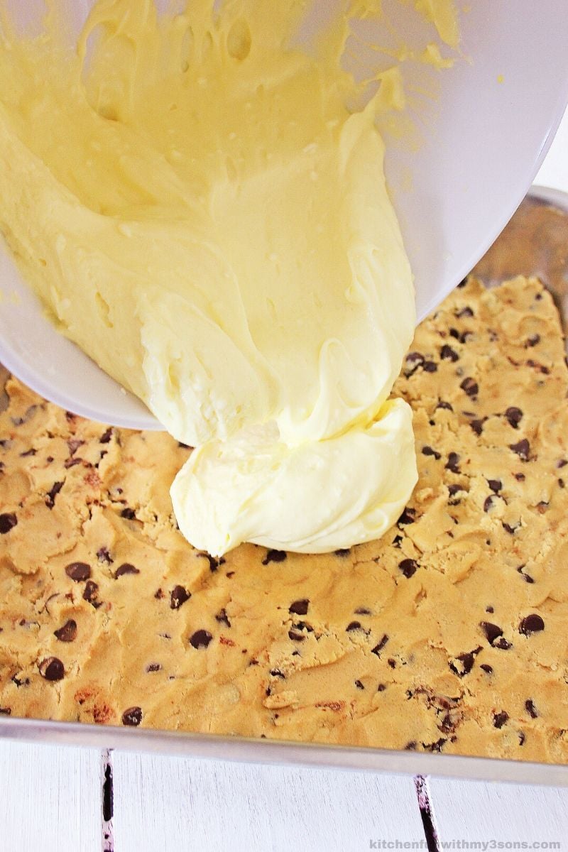 pouring cheesecake over chocolate chip cookie dough