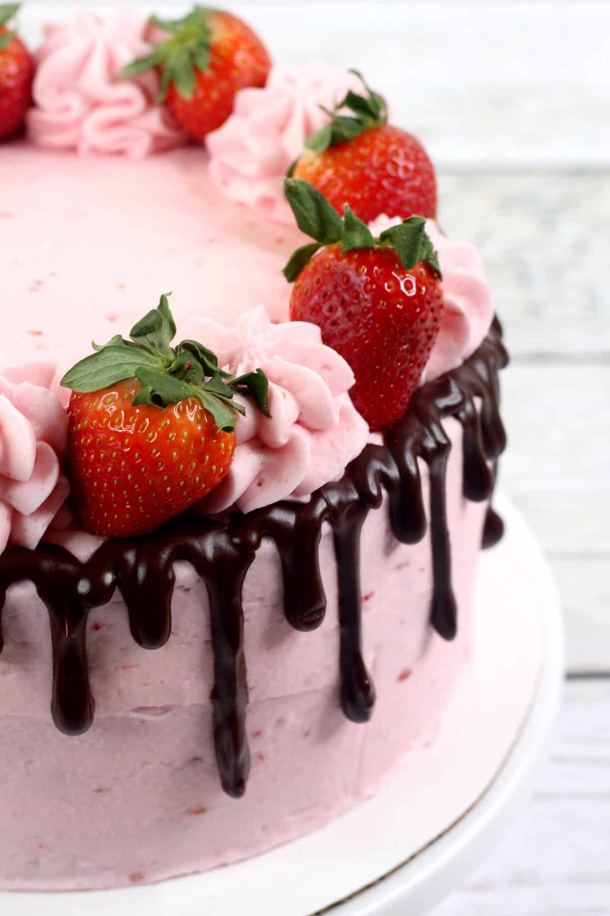 The side of a chocolate strawberry cake with ganache and fresh strawberries