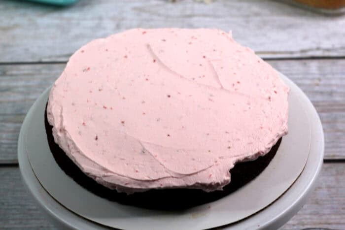 A layer of strawberry frosting on a round chocolate cake