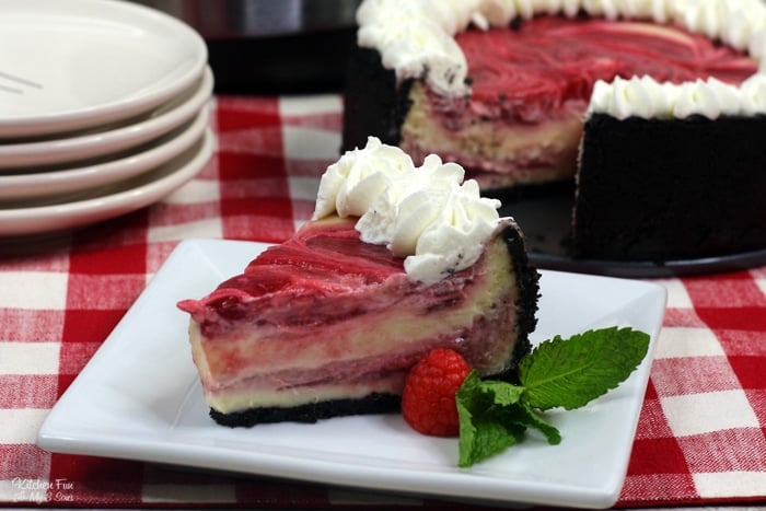 A slice of cheesecake on a plate garnished with whipped cream, with the rest of the cheesecake in the background.
