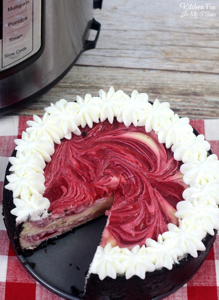 Overhead view of white chocolate raspberry cheesecake garnished with whipped cream, with a slice missing.