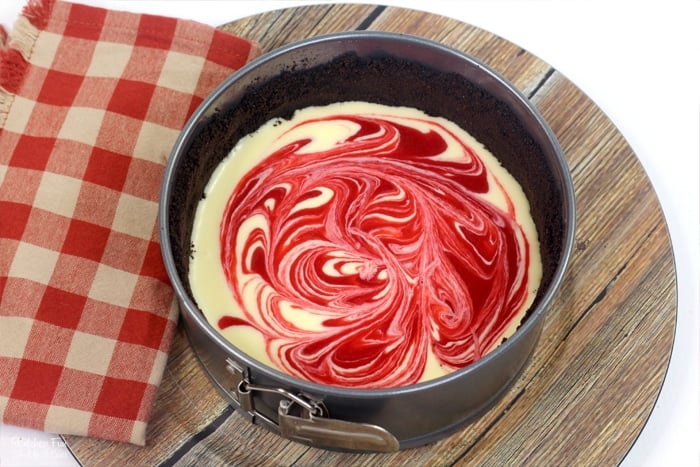 Cheesecake swirled with raspberry puree in a springform pan.