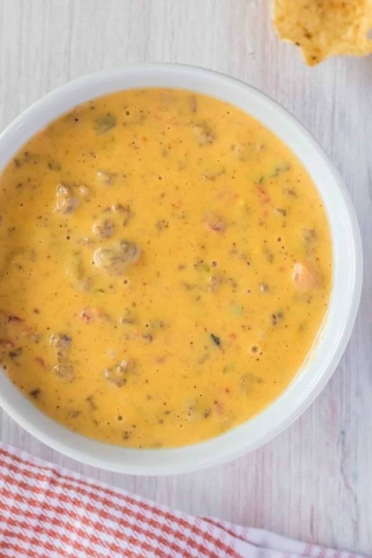 Velveeta cheese, Rotel, and ground beef come together in this cheesy and flavorful Hamburger Dip. Made in the slow cooker! Overhead view of a white bowl of cheesy hamburger dip
