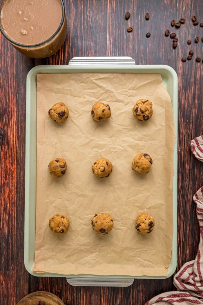 Balls of chocolate chip coffee cookie dough on a baking sheet