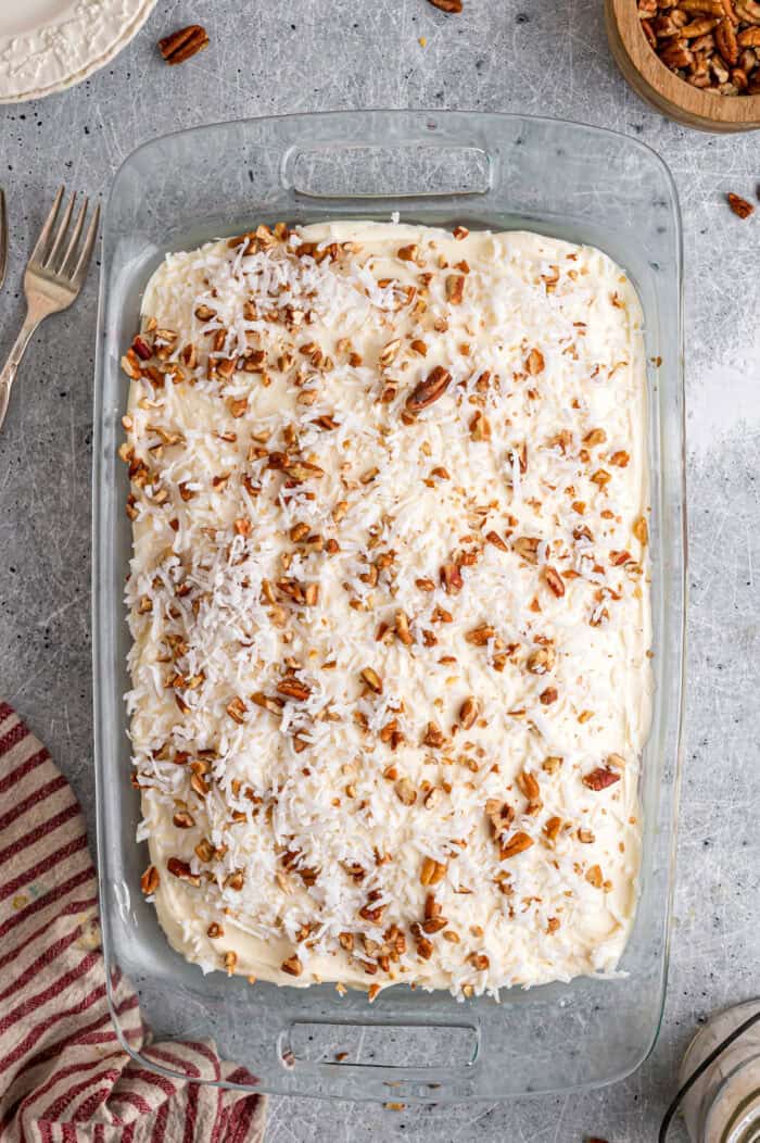 Tender, moist vanilla cake is dotted with coconut and pecans, then topped with cream cheese frosting in this Italian Cream Cake recipe. Overhead view of an Italian cream cake in a baking dish