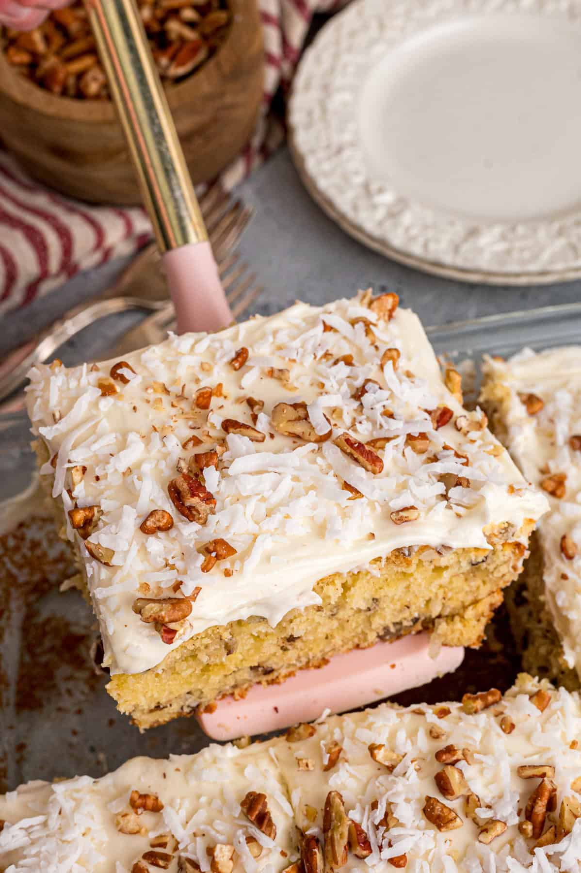 Tender, moist vanilla cake is dotted with coconut and pecans, then topped with cream cheese frosting in this Italian Cream Cake recipe. Serving a slice of Italian cream cake