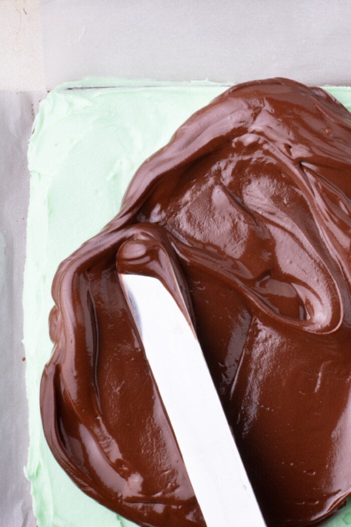 spreading chocolate ganache over the mint frosting