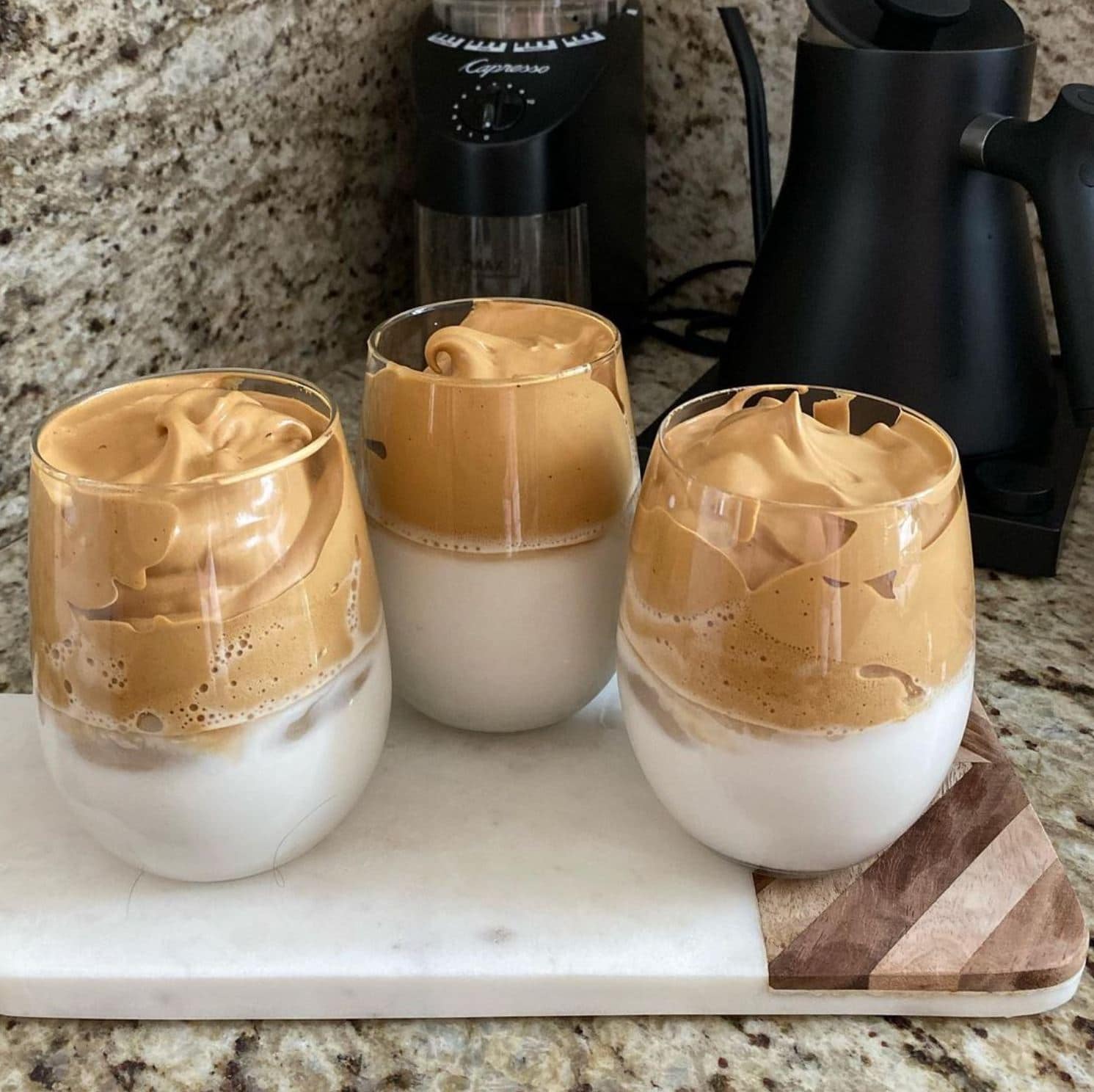 Three dalgona coffees in glasses on a counter.